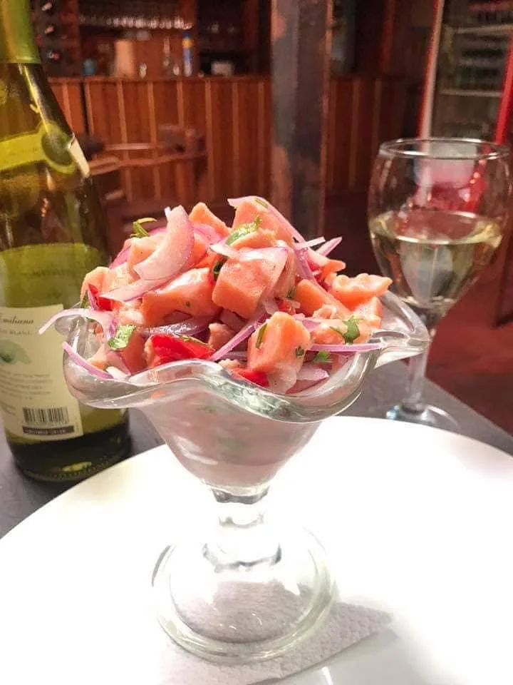 Preparación en copa con piezas de pescado, cebolla morada y hierbas