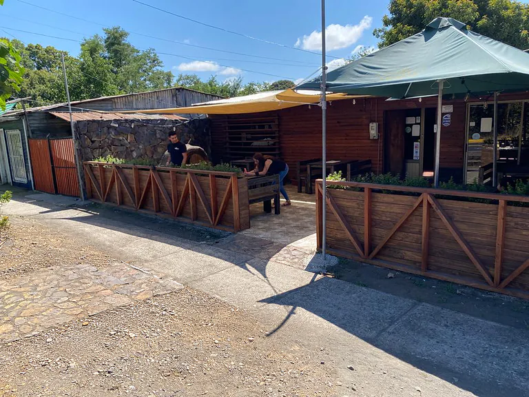 Exterior del restaurante de madera, con toldos y mesas al aire libre