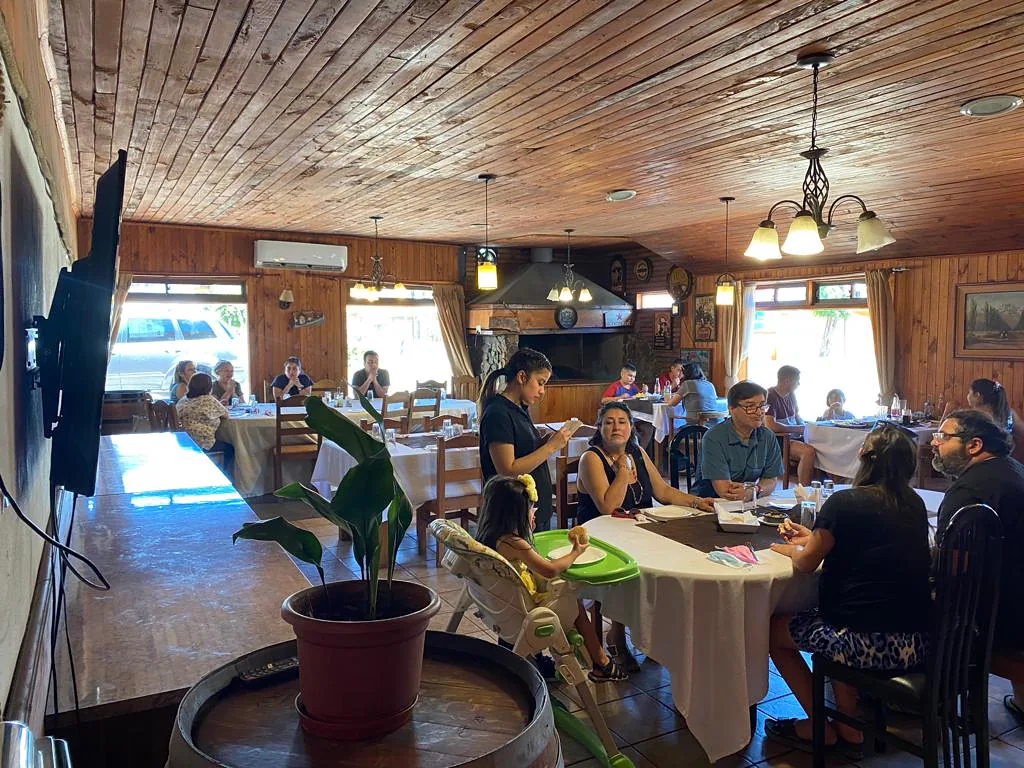 Salón de madera con mesas, lámparas y comensales